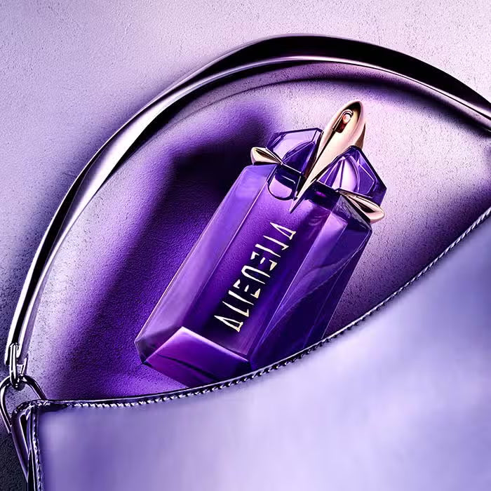 Mugler Alien Refillable Talisman EDP 30ml purple bottle with gold cap resting in a purple pouch on a lavender background.