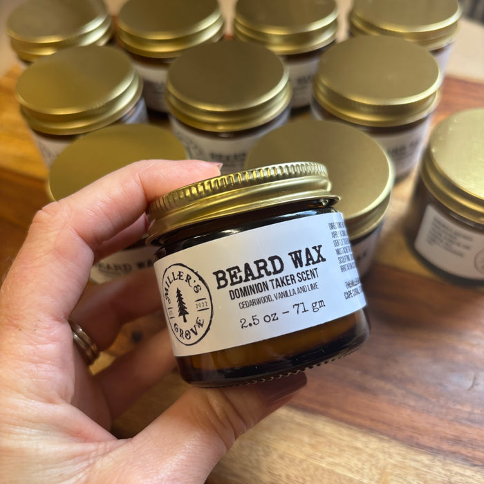 Hand holding a jar of beard wax with 'Miller's Grove' branding, surrounded by more jars on a wooden surface.