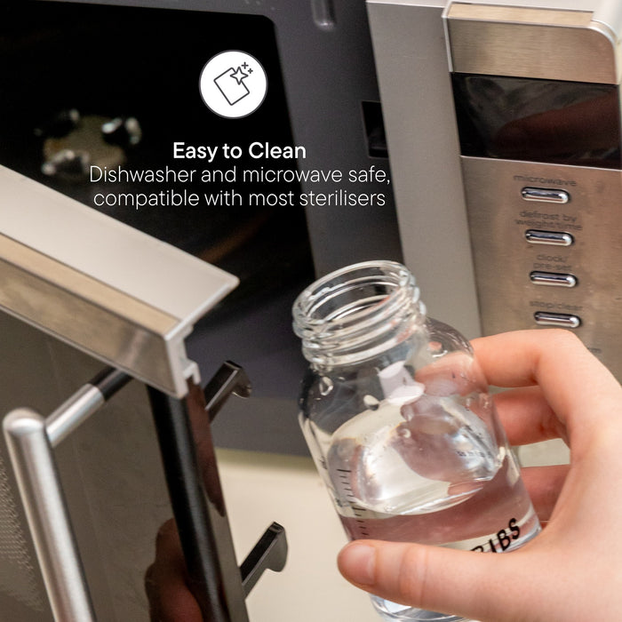 Hand holding BIBS Glass Baby Bottle near open microwave; text reads "Easy to Clean, Dishwasher and microwave safe, compatible with most sterilisers"