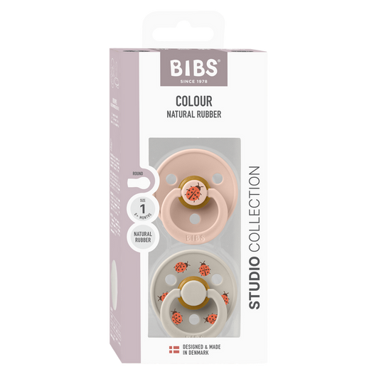 BIBS Studio Colour 2 Pack Ladybug pacifiers in blush and grey with ladybug prints, Size 1, in packaging on white background.