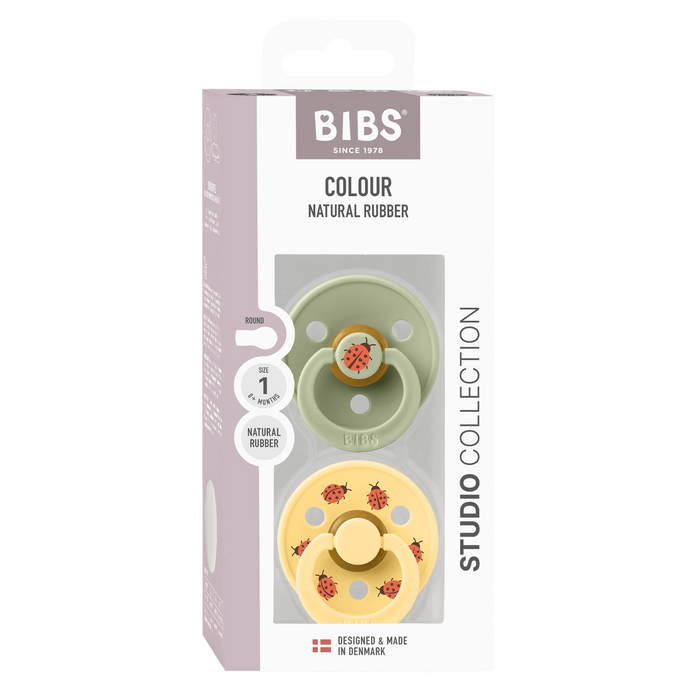 BIBS Studio Colour 2 Pack Ladybug pacifiers in sage and yellow, Size 1, in box on white background