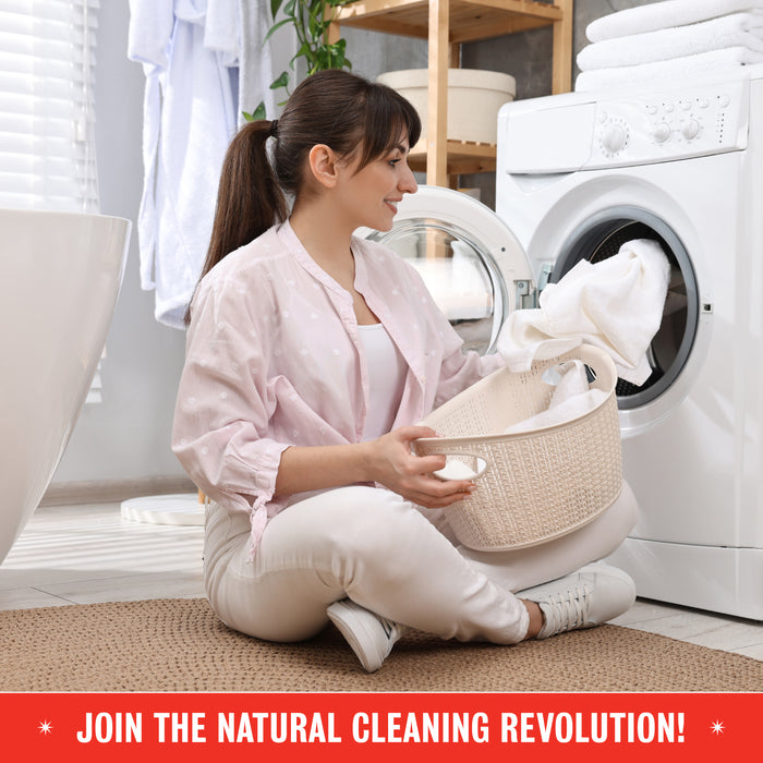 A woman in light clothing smiles as she loads white towels into a front-loading washer with Rebel Green Fresh Laundry Detergent Liquid - 3x Concentrated. Join the natural cleaning revolution with gentle ingredients!.