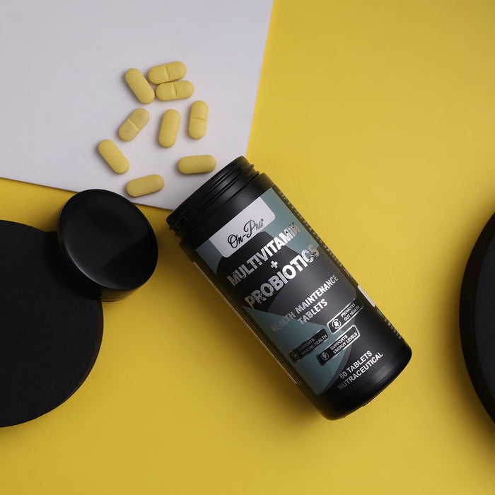 Black supplement bottle labeled 'Multivitamin + Probiotic' on a yellow surface with scattered tablets.
