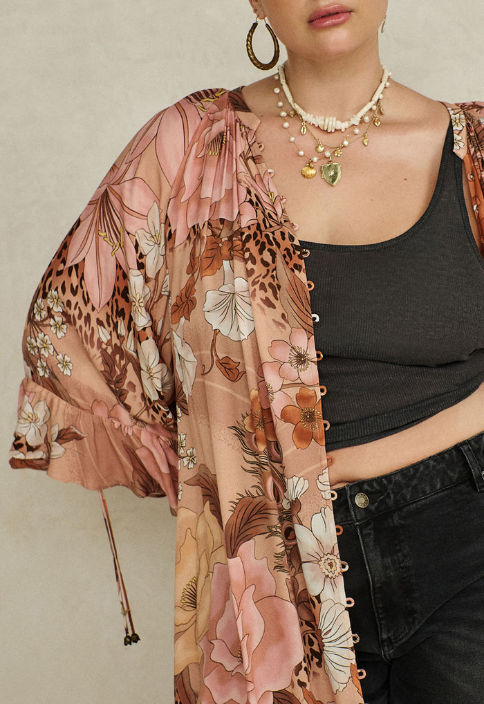 Close-up of rose quartz floral-print ECOVERO viscose gown showing button front, ruffle sleeve and elastic cuff with ties