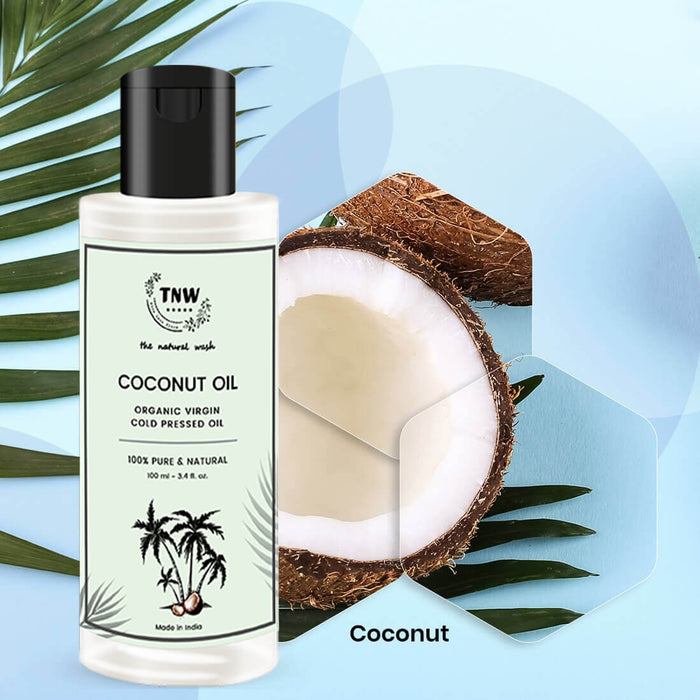 Bottle of coconut oil with a halved coconut and palm leaves on a light blue background