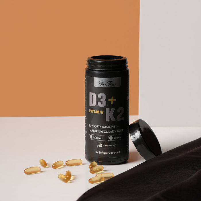 Black supplement bottle labeled D3+ Vitamin K2 with capsules on a white surface.