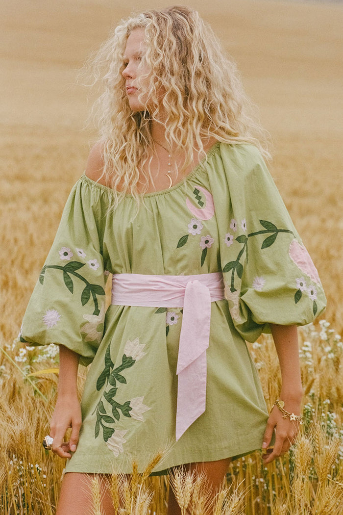 Front view of Wonderland Dress in Lime Essence with floral appliqué, puff sleeves, elastic neck, and pink sash belt